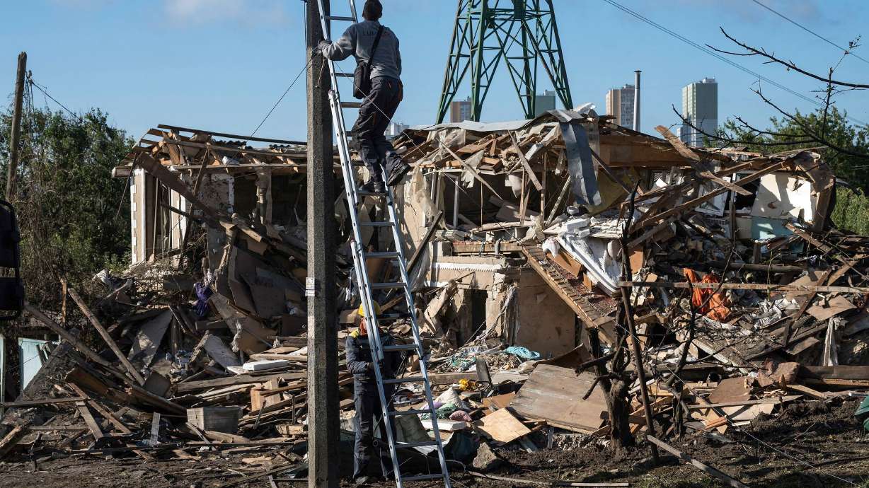 Electricians work to restore the power grid in front of a destroyed private house in the Kyiv region. A a 14-year-old was killed in the attack on Sept. 30.