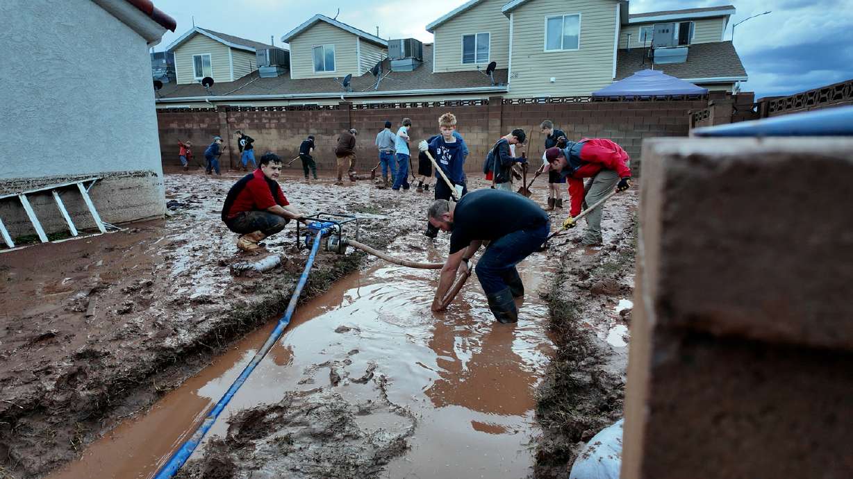 Volunteers help a homeowner clear mud from around her home after flooding in Hurricane on Oct. 22.