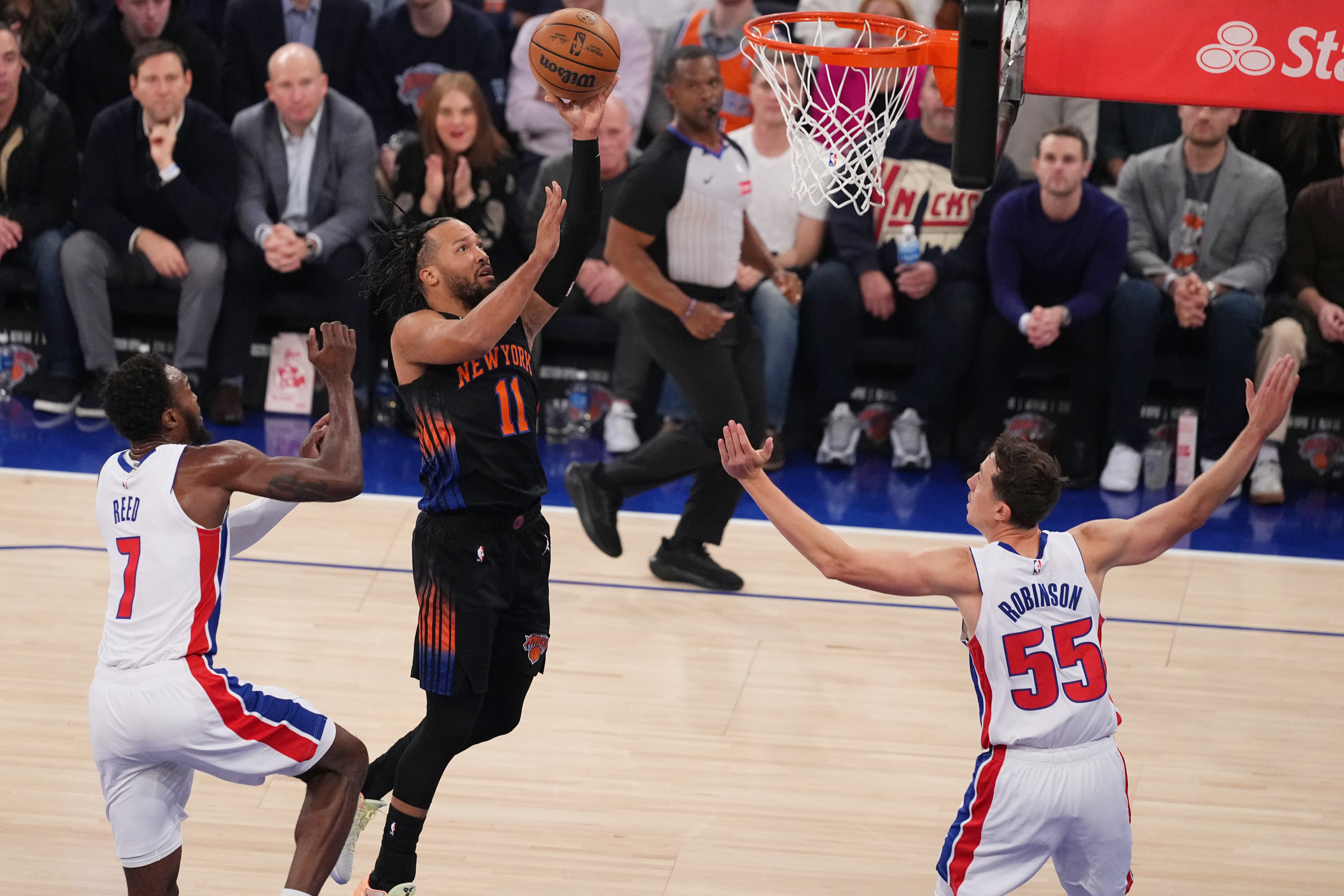 New York Knicks' Jalen Brunson (11) drives past Detroit Pistons' Paul Reed (7) and Duncan Robinson (55) during the first half of an NBA basketball game Tuesday, Oct. 27, 2026, in New York. 