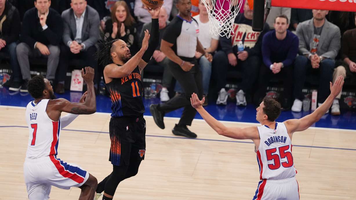 New York Knicks' Jalen Brunson (11) drives past Detroit Pistons' Paul Reed (7) and Duncan Robinson (55) during the first half of an NBA basketball game Tuesday, Oct. 27, 2026, in New York.