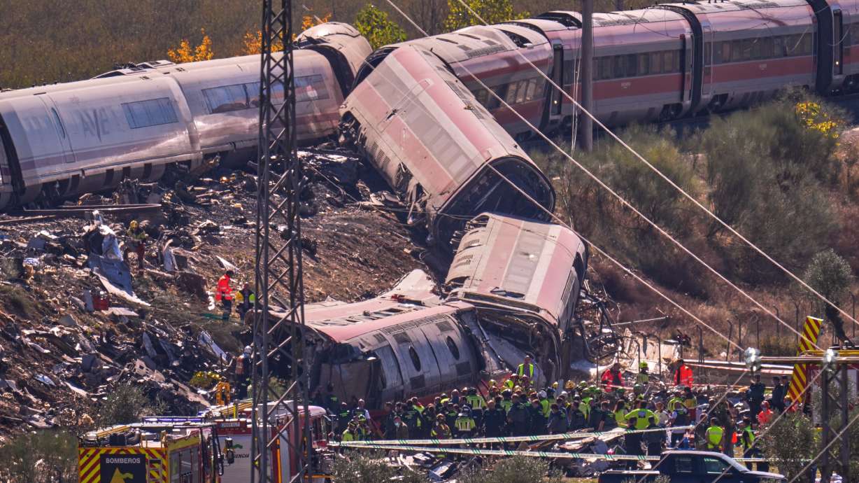 Emergency services work at the scene of a collision between two trains in Urda, Spain, Wednesday. Two cars were derailed, leading to at least 68 people being killed.