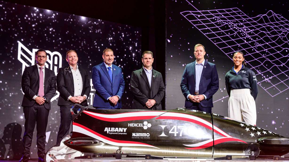 Utah aerospace and defense leaders, along with Team USA bobsled member Kaysha Love, pose for a picture with a newly unveiled bobsled built from the same advanced materials used to build aircraft, missiles and unmanned systems.