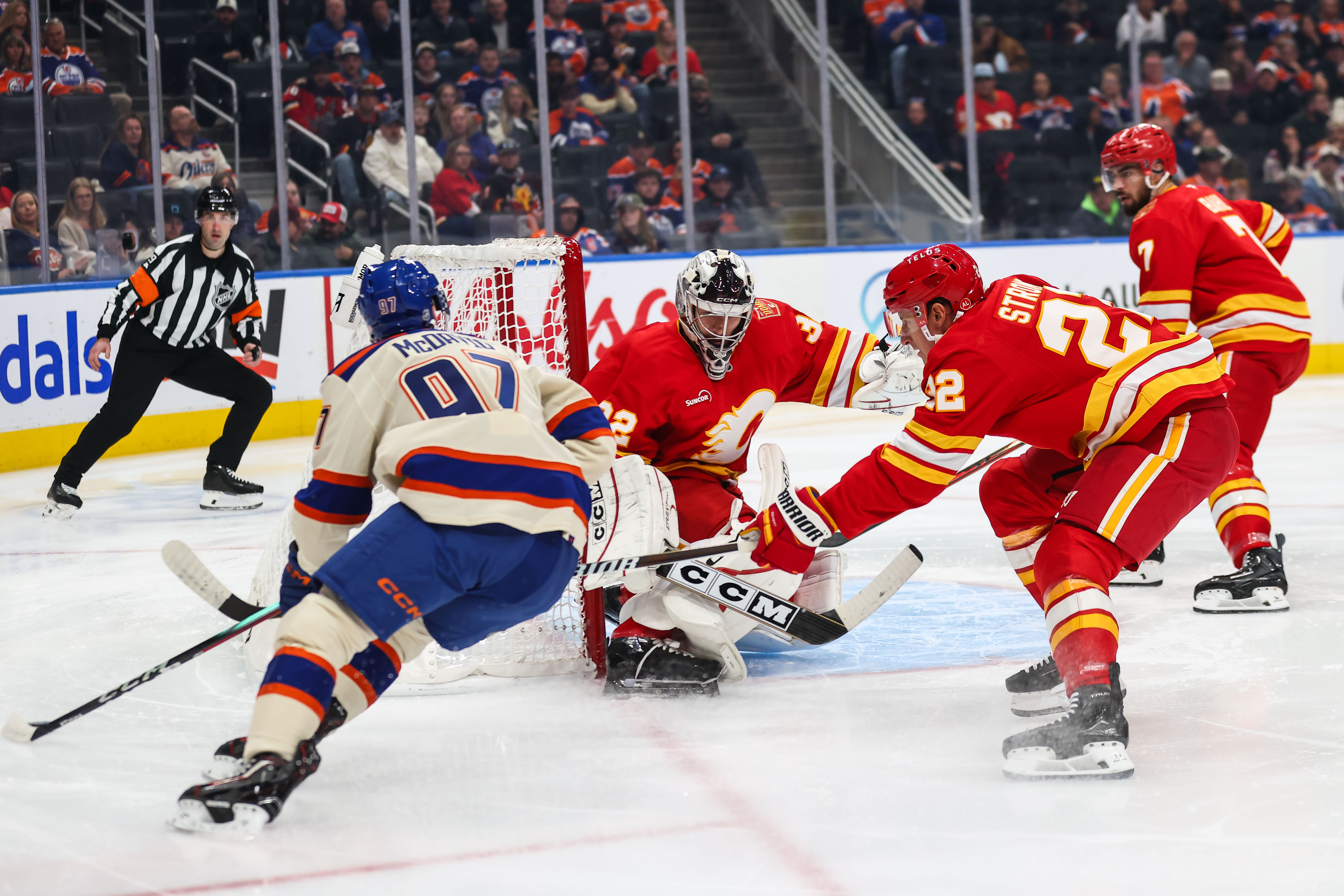 Edmonton Oilers' Connor McDavid, left, looks for an opportunity against Calgary Flames goaltender Dustin Wolf, center, during the second period of an NHL hockey game in Edmonton, Alberta, Wednesday, Oct. 28, 2026. 