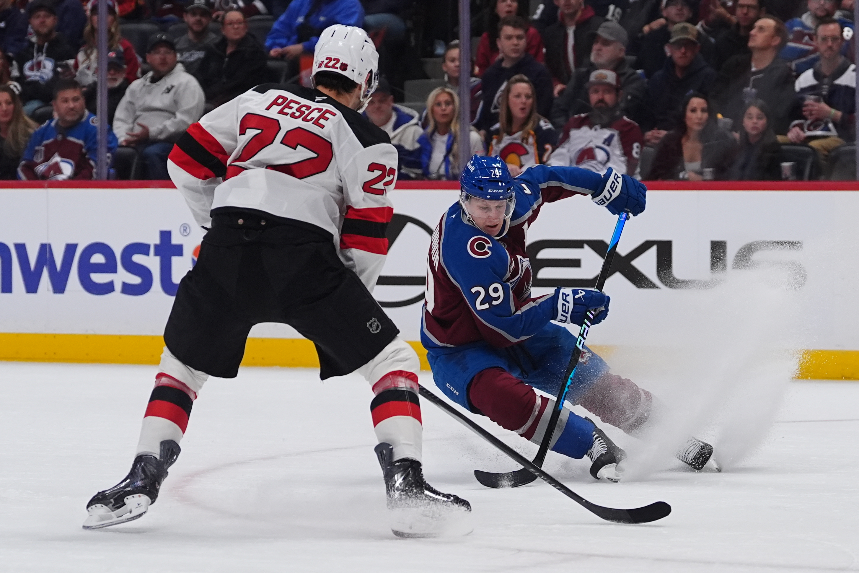 Colorado Avalanche center Nathan MacKinnon, right, looks to pass the puck as New Jersey Devils defenseman Brett Pesce covers in the first period of an NHL hockey game Wednesday, Oct. 28, 2026, in Denver. 