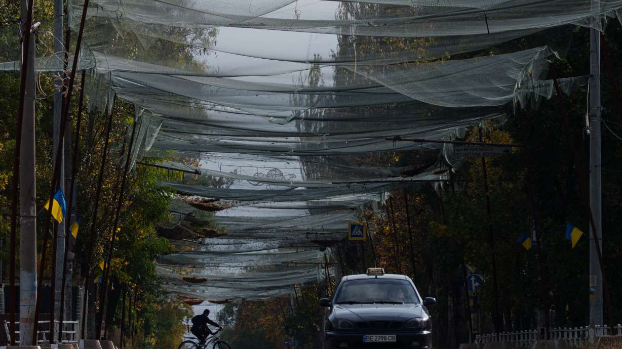 A local man rides a bicycle beneath anti-drone nets stretched over a street during a local ceasefire related to a humanitarian aid mission in Oleshky, in Kherson, Ukraine, Wednesday.