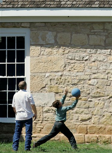 A young member of the Fundamentalist Church of Jesus Christ of Latter-Day Saints reaches up for a ball that was thrown onto the roof as he plays with an unidentified man at the group's temporary housing in Fort Concho National Historic Landmark, in San Angelo, Texas, Monday, April 7, 2008. More than 400 children were taken into state custody from a polygamist sect in what authorities described Monday as the largest child-welfare operation in Texas history. (AP Photo/Tony Gutierrez)